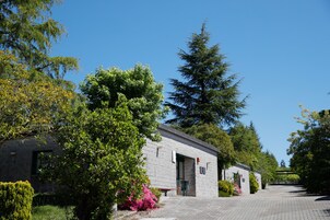 Un edificio de piedra con puerta y ventanas, rodeado de árboles y arbustos.