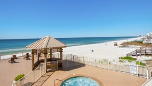 A beachside resort with a wooden gazebo, a pool, and a view of the beach and ocean.