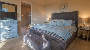 Un dormitorio con una cama grande, un aparador, un espejo y un reloj en la pared.