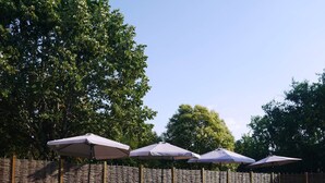 A swimming pool with lounge chairs and umbrellas, surrounded by a stone wall and trees. - The Clairette de Gascogne, space and comfort (CONDOM)