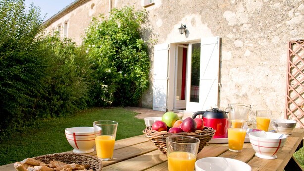 A wooden table set with breakfast items including fruit, juice, and bread. - The Clairette de Gascogne, space and comfort (CONDOM)