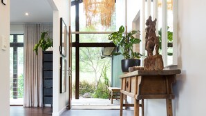 A spacious hallway with a wooden floor, a hanging light fixture, and a wooden bench with a statue. - Luxurious retreat in Pullenvale (Pullenvale)