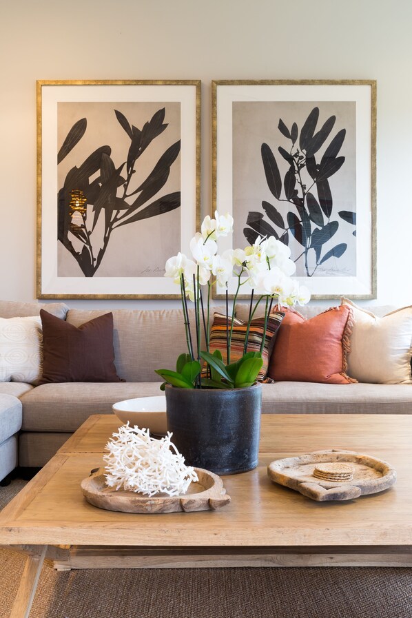 Un salon comprenant un canapé, une table basse et deux reproductions botaniques encadrées accrochées au mur.