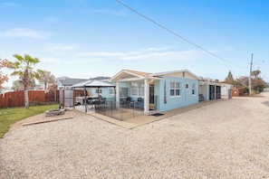 A single-story house with a covered patio, a gravel driveway, and a wooden fence.
