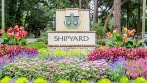 Een bord met de tekst 'SHIPYARD' met een decoratief embleem, omringd door een kleurrijke bloemenborder.