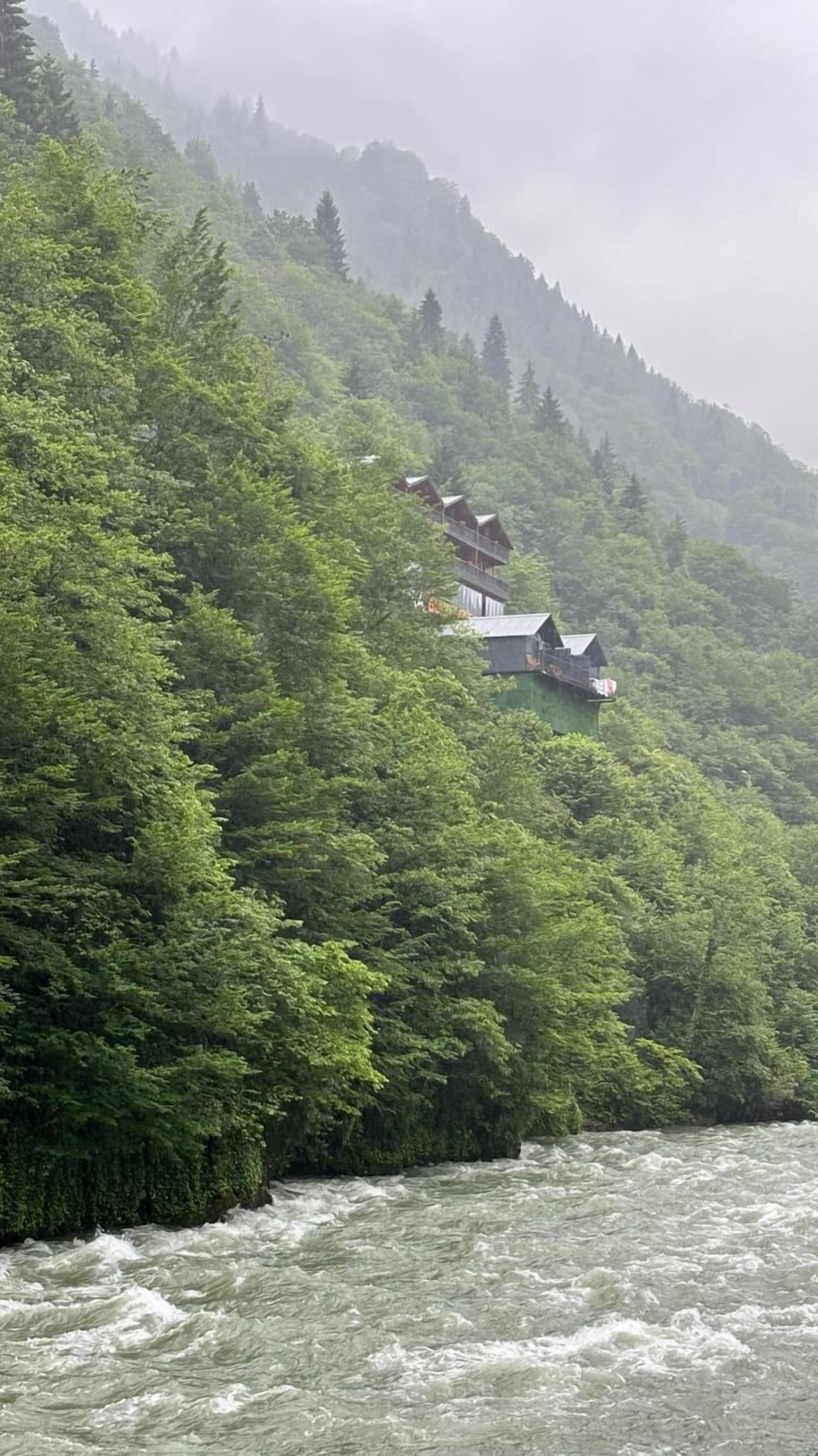 Cabañas alineadas en una colina, con un río al frente.