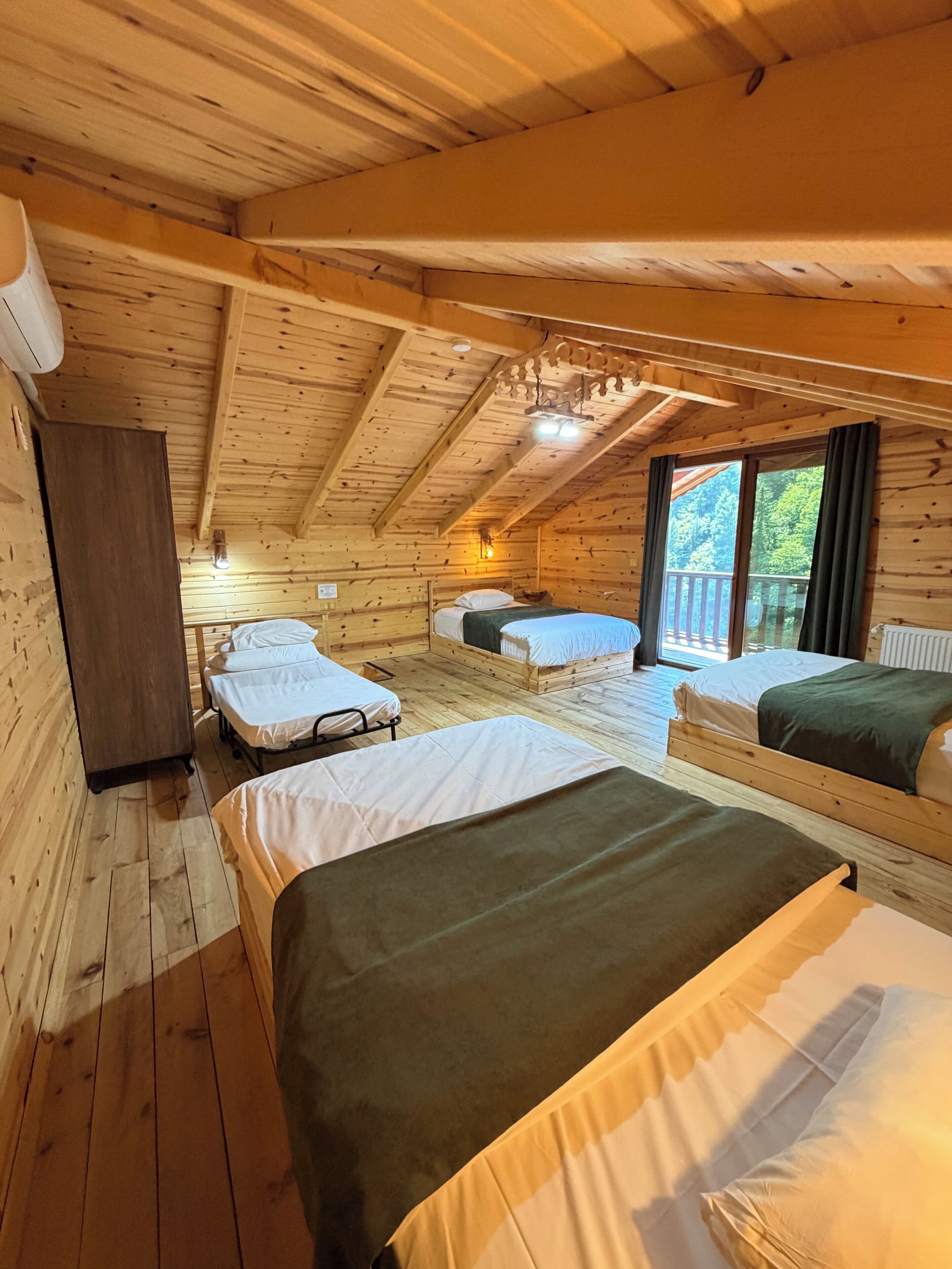 Een chalet met drie bedden, houten wanden en een schuin dak.