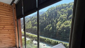 A room with a large window, a wooden wall, and a bathtub. - Hira Bungalov (Camlihemsin)