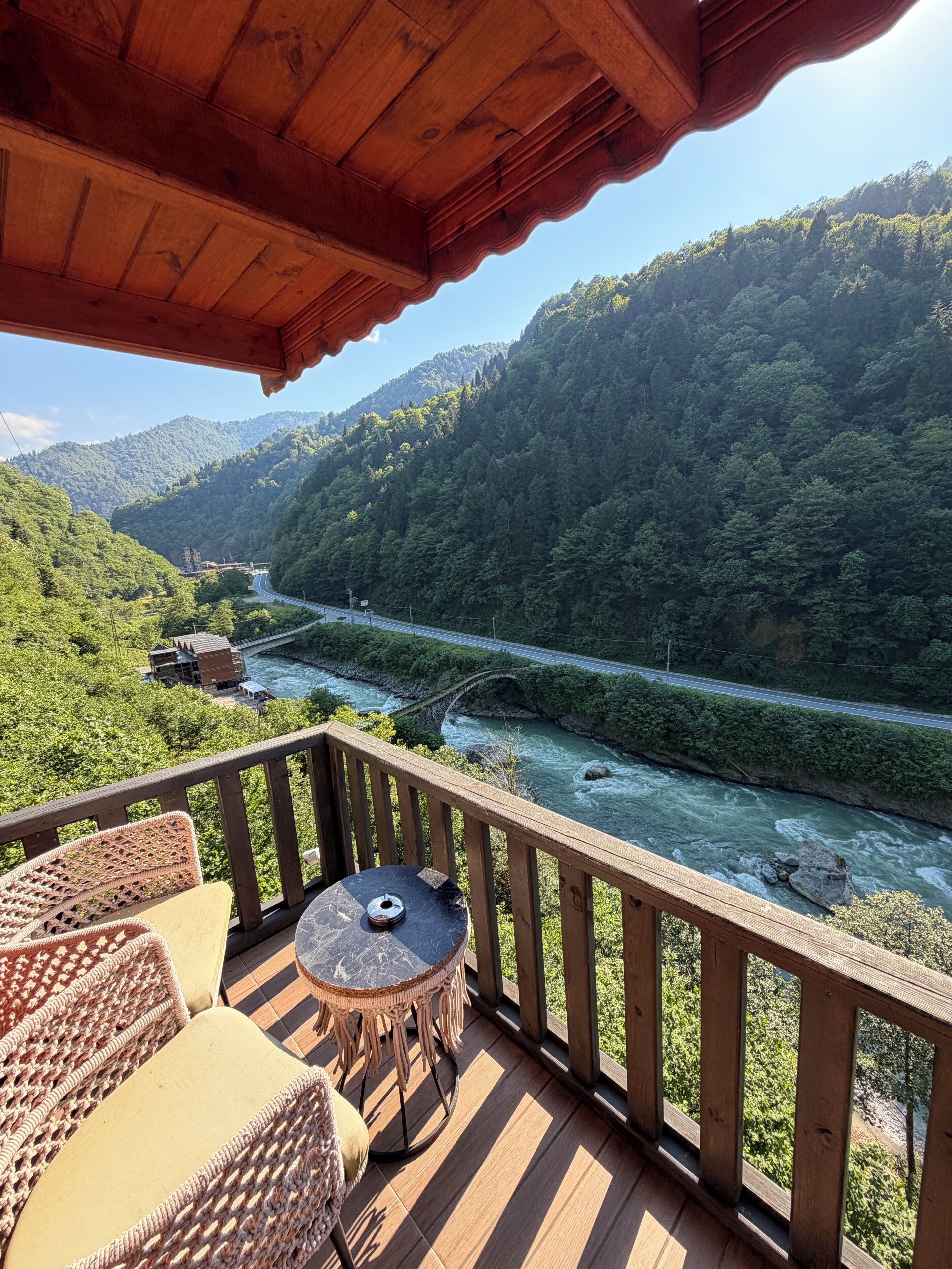 Une terrasse en bois offrant une vue sur une rivière et des montagnes.