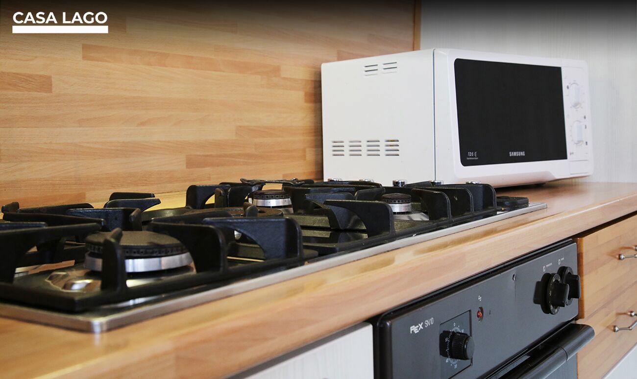 A kitchen with a gas stove, a microwave, and a range hood.