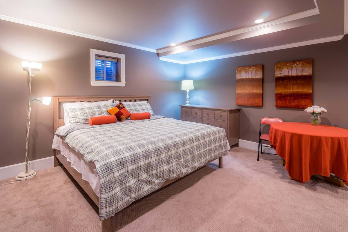 Een slaapkamer met een bed, nachtkastje, lamp en kunst aan de muur.
