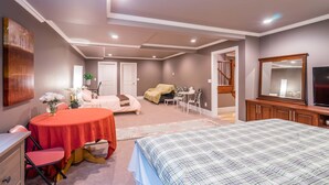 Un dormitorio con cama, escritorio, silla, una mesita con una planta y televisor.