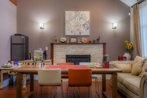 Un comedor con chimenea de piedra, refrigerador y sofá.