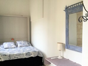 A bedroom with a bed, a nightstand, a lamp, and a mirror. - Clos des Arts Hanging (Avignon)