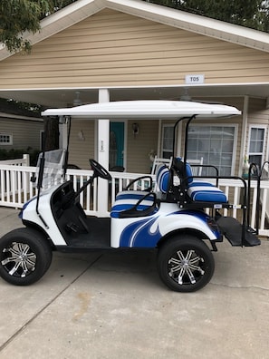 A golf cart parked in front of a house with a porch and a mailbox labeled T5.