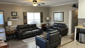 A spacious living room with two leather sofas, a dining area with a table and chairs, a ceiling fan, and nautical-themed wall decor. - Comfortable 3 BR / 2 Bath n convenient location (Myrtle Beach)