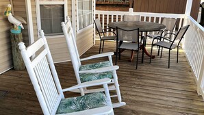 A wooden deck with white rocking chairs and a round table with chairs. - Comfortable 3 BR / 2 Bath n convenient location (Myrtle Beach)