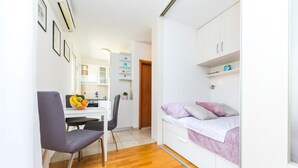 A compact room with a bed, a desk, and a chair. There is a small kitchenette in the background. - Close to Znjan beach, spacious studio with balcony (Split)