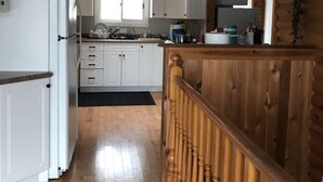 Una cocina con armarios blancos, una escalera de madera y un tragaluz.