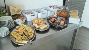 A buffet table with various food items including bread, pastries, and a plate of sliced bread with a knife. - Still White Beach **** Wonderful room facing the sea (Avola)
