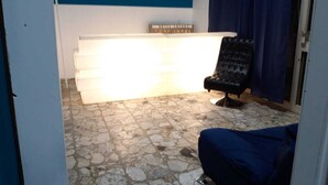 A room with a stone floor, a black chair, a white reception desk, and a blue wall. - Still White Beach **** Wonderful room facing the sea (Avola)