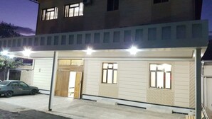 Un bâtiment à deux étages, doté d’un toit plat, de nombreuses fenêtres et d’une voiture garée devant.