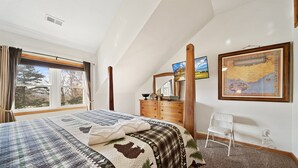 Une chambre à coucher avec un grand lit, une commode, une chaise et une carte accrochée au mur.