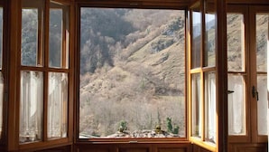 A room with a bay window overlooking a mountainous landscape.