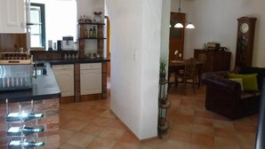 A kitchen with a wine rack, a dining area with a table and chairs, and a living room with a sofa.