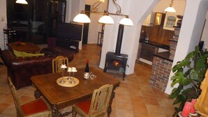 A cozy living room with a fireplace, a dining table with candles, and a television in the background.