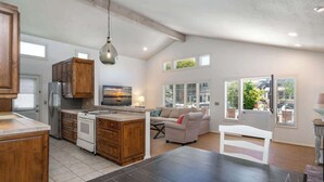 Una cocina amplia con armarios de madera, una isla central y un comedor con mesa y sillas.