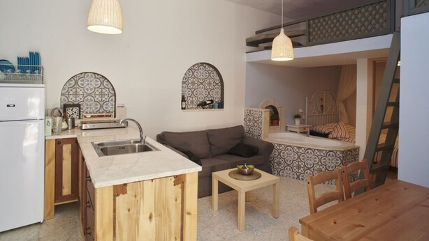 A compact living space with a kitchenette, a sofa, a dining table, and a small island with a sink. - Jerusalem Boutique holiday home in Katamon (Jerusalem)