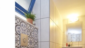A bathroom with a toilet, patterned wall tiles, a red rug, and a cabinet with a mirror. - Jerusalem Boutique holiday home in Katamon (Jerusalem)