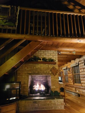 A log cabin interior with a fireplace, wooden beams, and a TV. - Shenandoah River = Less Stress (Luray)