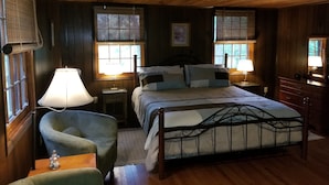 Une chambre confortable dans un chalet en bois, avec un grand lit, deux tables de chevet avec des lampes, une chaise et une commode.