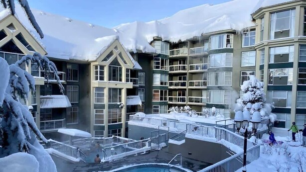 A hotel with a pool surrounded by snow-covered balconies and buildings. - Woodrun Lodge condo w/ pool & hot tub (Whistler)