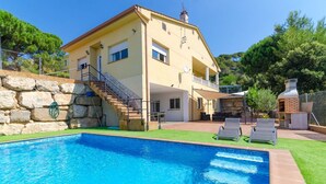 A two-story house with a swimming pool, outdoor seating, and a stone wall. - Club Villamar - Precious villa with private pool located in a residential area, a perfect electio... (Lloret de Mar)