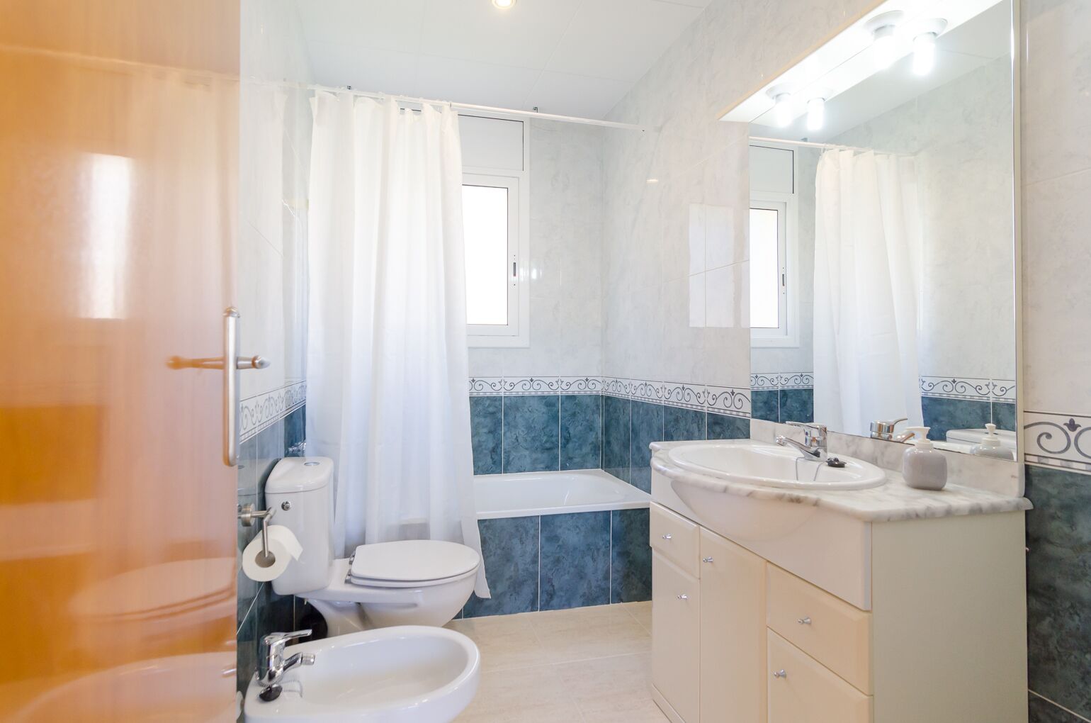 A bathroom with a toilet, bidet, bathtub, and two sinks.