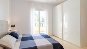 A bedroom with a bed, nightstand, lamp, and a sliding door to a balcony. - Club Villamar - Precious villa with private pool located in a residential area, a perfect electio... (Lloret de Mar)