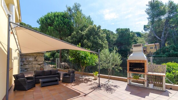 An outdoor patio with a barbecue grill, wicker furniture, and a stone wall. - Club Villamar - Precious villa with private pool located in a residential area, a perfect electio... (Lloret de Mar)