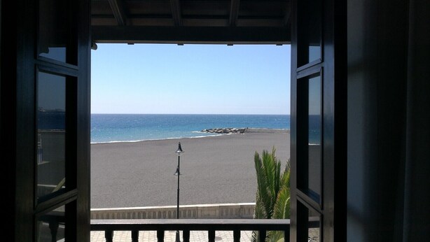 Vue sur une plage depuis un balcon couvert doté d’une balustrade.