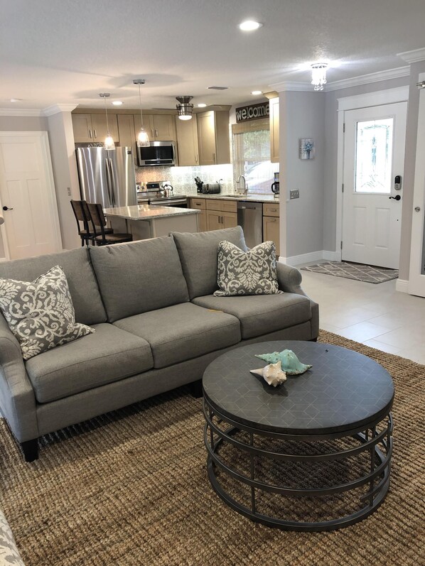 A living room with a gray sofa, patterned pillows, and a round coffee table with decorative items.