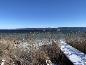 Un paysage enneigé avec un lac gelé, des roseaux et un ciel bleu clair.