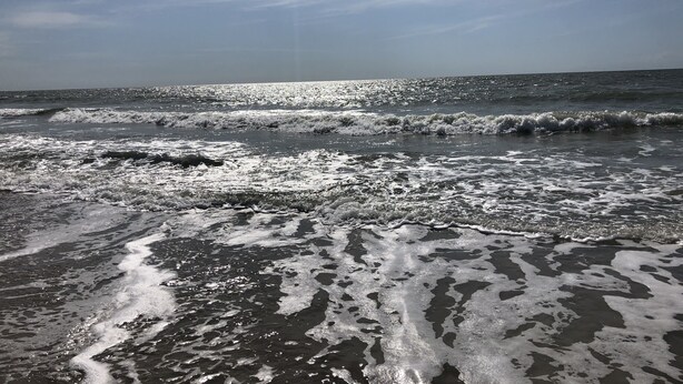 Una playa con olas y cielo despejado.