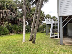Enjoy outdoor relaxation on the covered porch, surrounded by lush palm trees and a well-maintained lawn.
