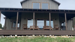 Eine rustikale Holzhütte mit einer Veranda, großen Fenstern und Sitzgelegenheiten im Freien.