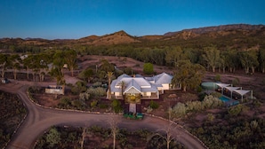 A large house with a prominent garage and a swimming pool, surrounded by a hilly landscape and sparse vegetation. - Arkaba Homestead (Hawker)