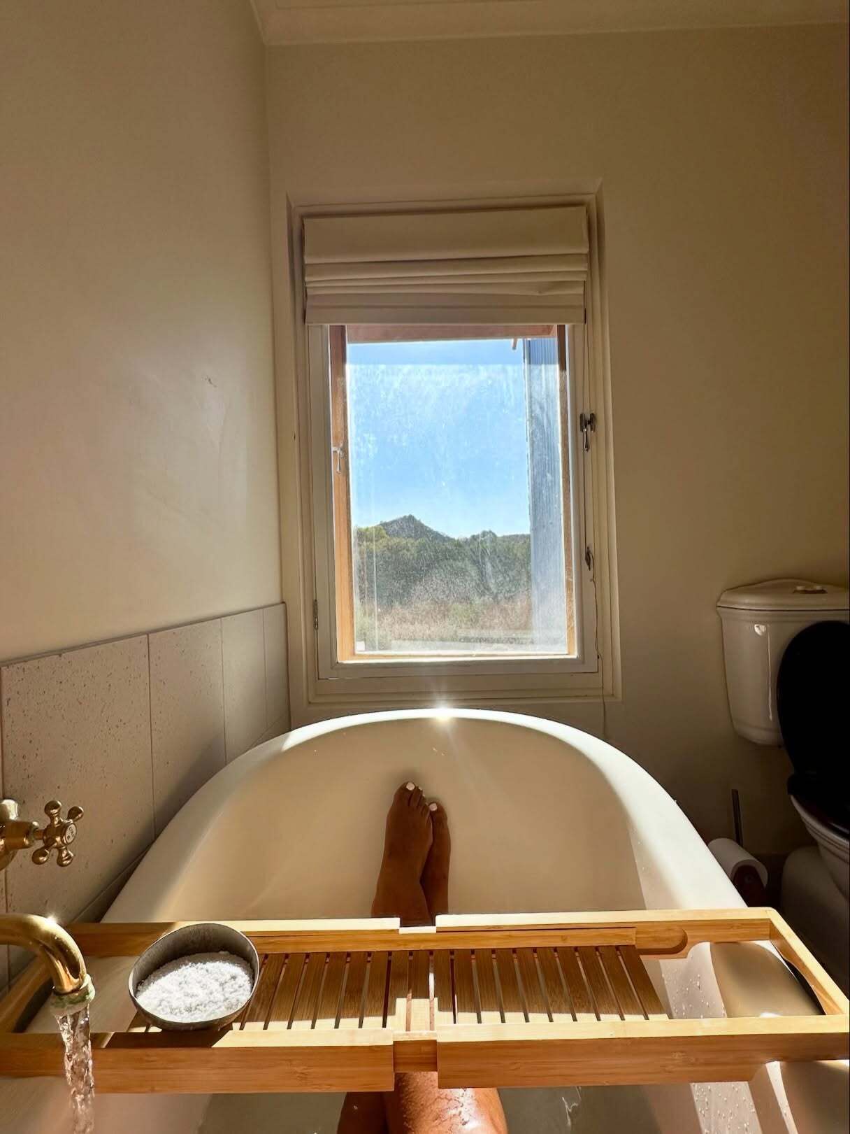 A bathroom with a bathtub, a window, and a wooden drying rack.