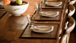 A dining table set with plates, glasses, and a bowl of fruit. - Arkaba Homestead (Hawker)