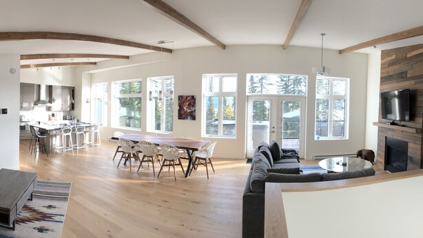 A spacious living area with a kitchen, dining table, and seating arrangements. - New built, modern ski-in/ski-out home with great views of Columbia River Valley (Golden)